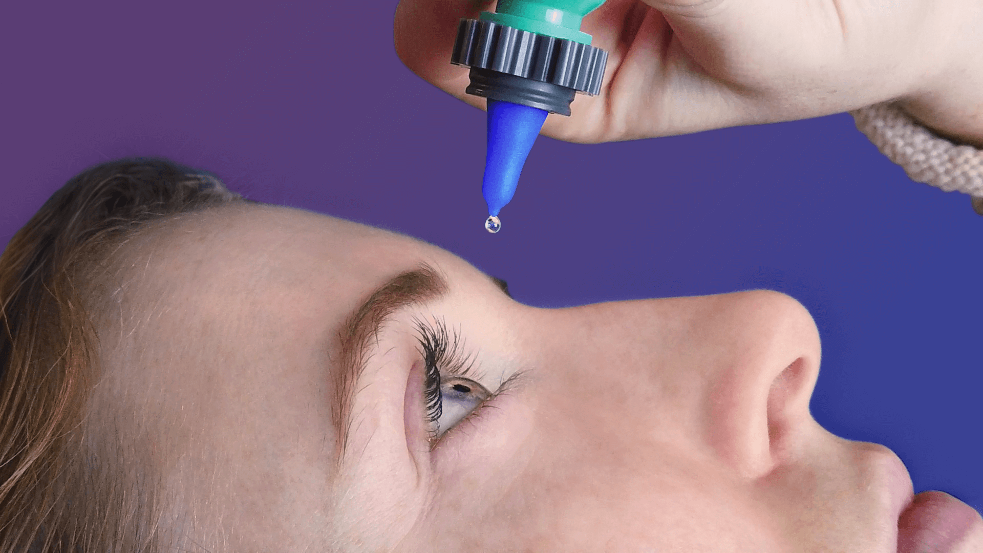 A person lying down with a focused view on their face and eye. They are about to receive an eye drop from a blue bottle held above their eye. The background is a gradient of blue and purple.