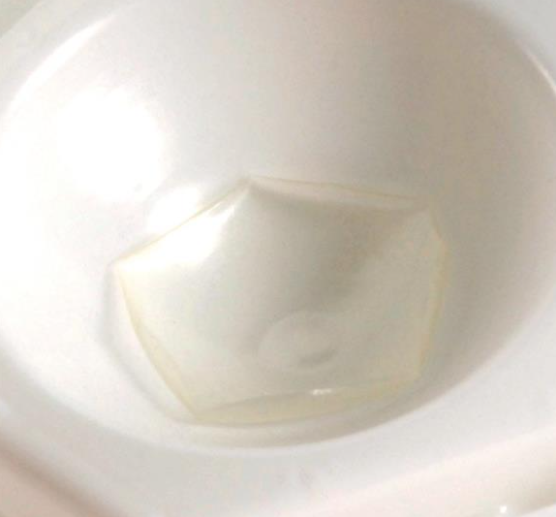 An Oasis Collagen Shield from Oasis Medical, hexagonal and translucently soft like ocular tools, sits flexibly in a white sink.