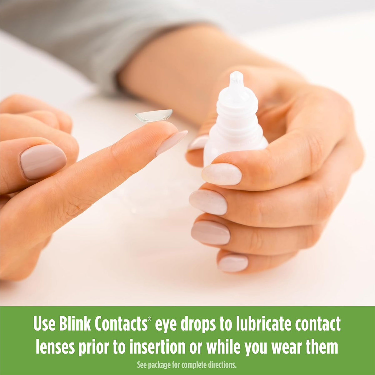 A person holds a contact lens near an open Blink Contacts Lubricating Eye Drops (10ml) bottle by Bausch + Lomb. The text suggests using these drops to improve lens comfort before insertion or during wear.