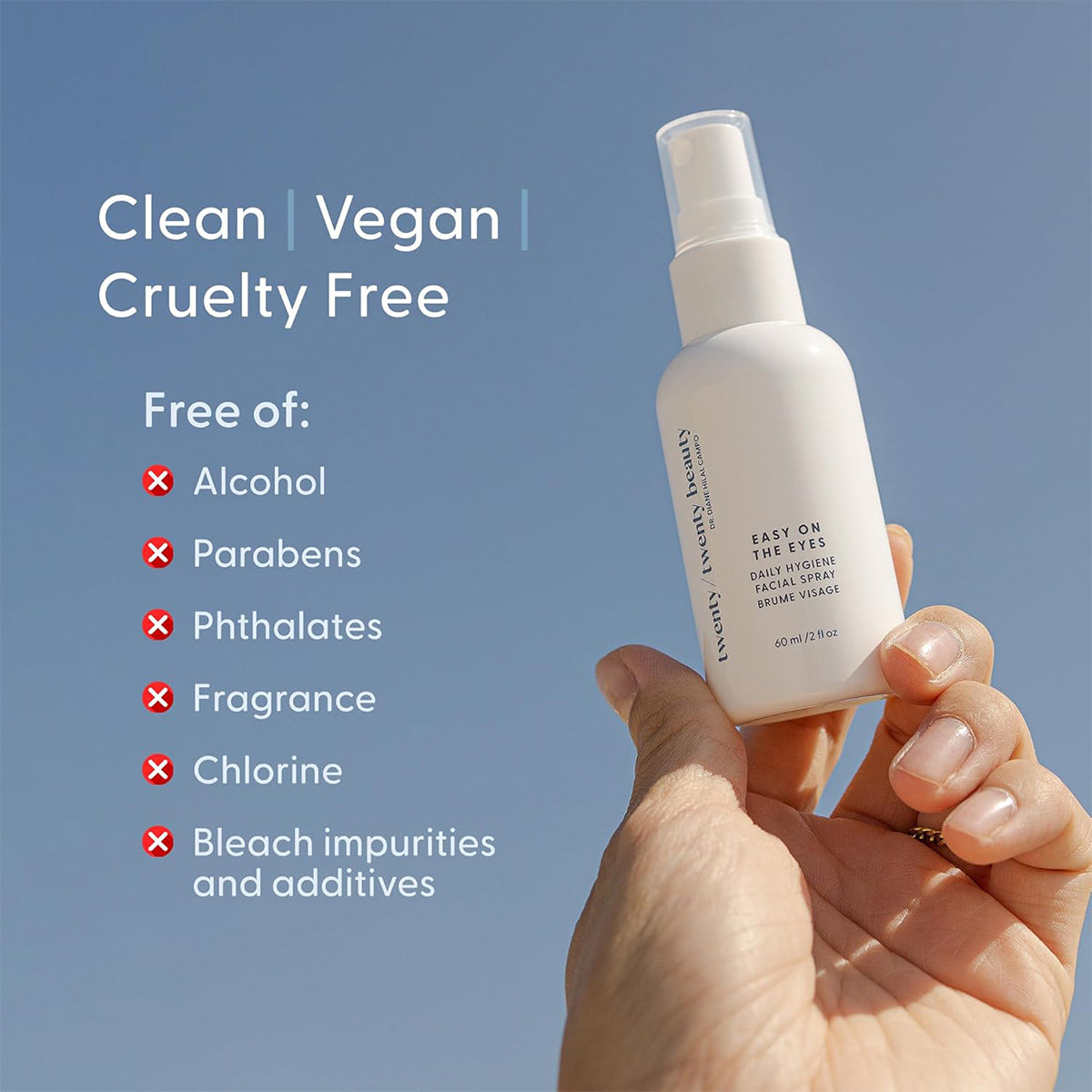 Against a blue sky, someone holds a bottle of Twenty Twenty Daily Hygiene Facial Spray (Hypochlorous Spray) (60ml). The features: Clean, Vegan, Cruelty-Free with a calming mist for eye and skin health. Its free of alcohol, parabens, phthalates, fragrance, chlorine, and additives.