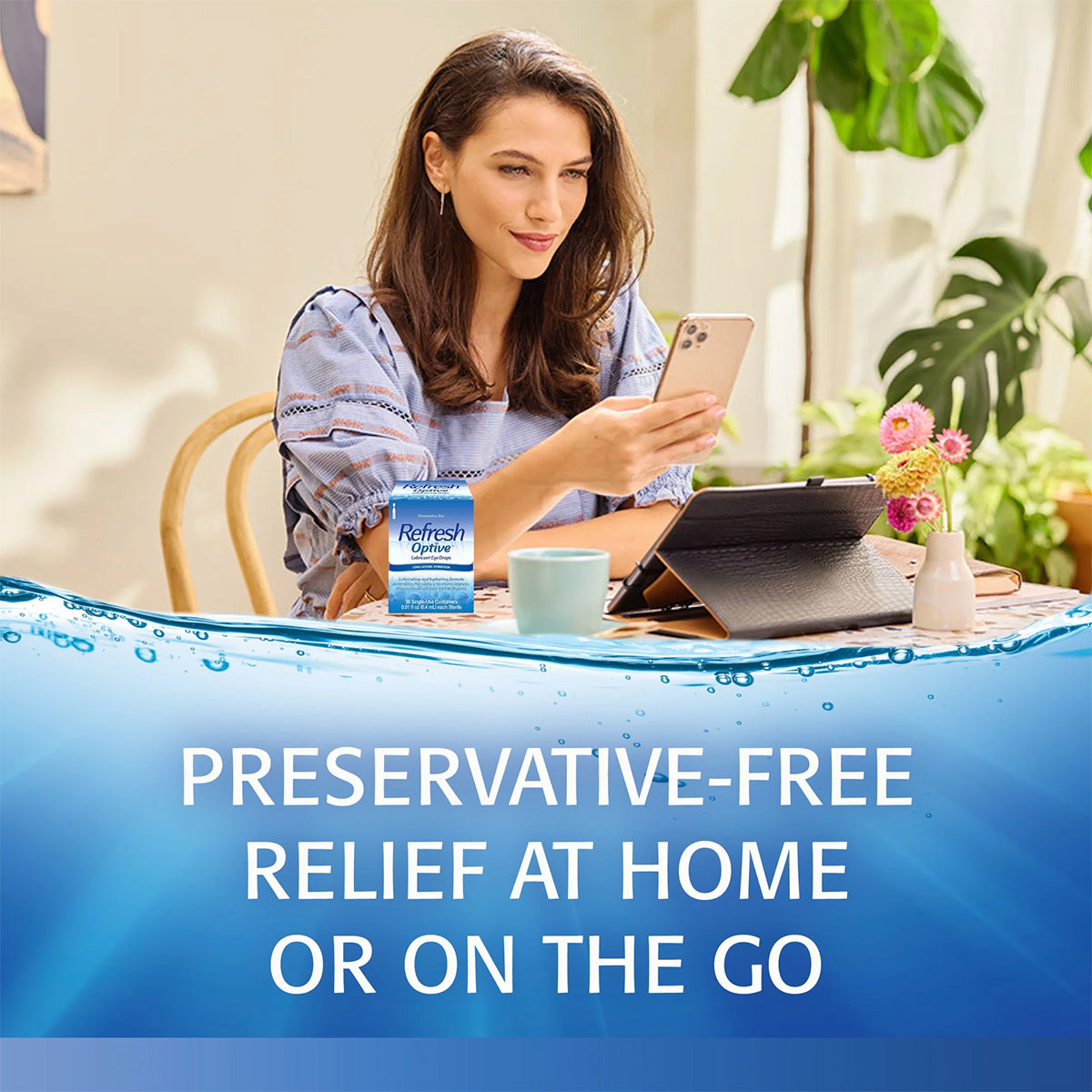 A woman sits with a smartphone, a tablet, and coffee mug on the table. Close by, a box of Abbvies Refresh Optive Lubricant Preservative Free Eye Drops (30 vials) provides HydroCell™ technology for soothing dry eyes at home or on the go.