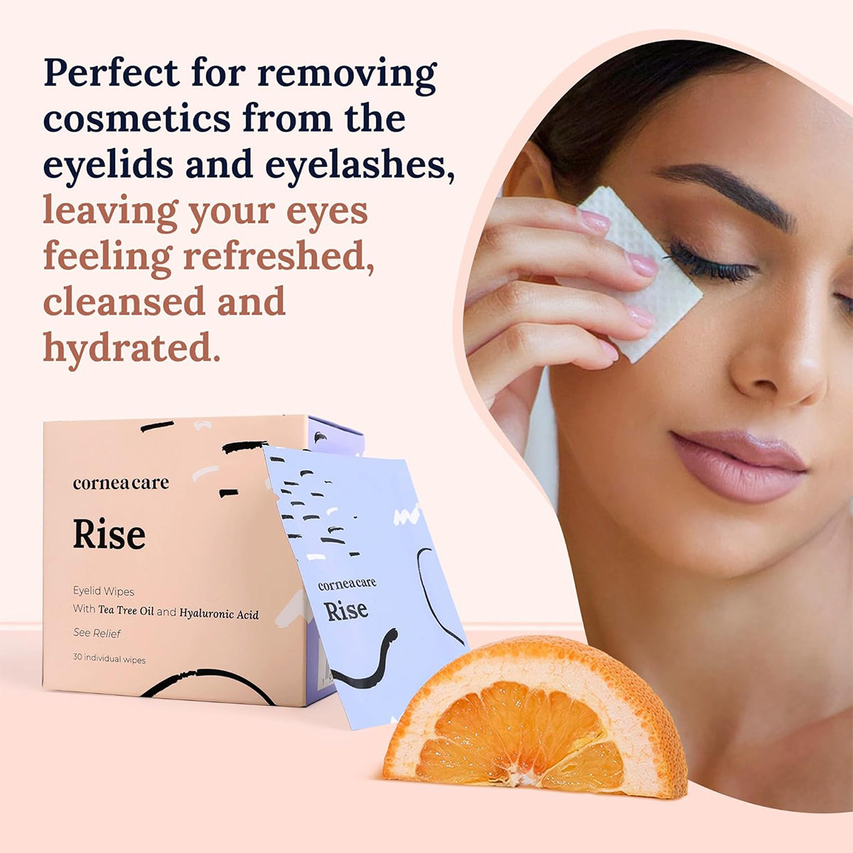 A woman uses a cosmetic wipe near a box of CorneaCare Wipes with Tea Tree Oil (30ct). Text: Ideal for cleansing eyelids and eyelashes, leaving them refreshed and hydrated. Infused with tea tree oil for extra comfort. Orange slice visible. Brand: CorneaCare.