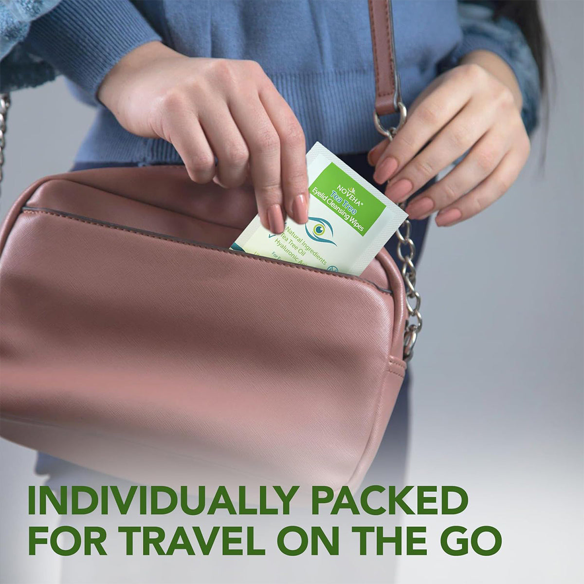 A person in a blue top places a Noveha: Soak Up packet into a pink handbag. The bottom text reads, Individually packed for travel on the go. Ideal for ocular hygiene and soothing dry, itchy eyes with tea tree oil, HA, green tea & chamomile from NOVEHA Eyelid & Lash Wipes.