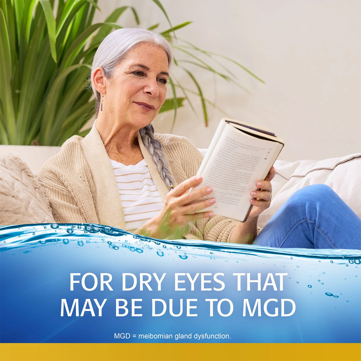 An older person with long gray hair sits on a couch reading and smiling. The text reads, For dry eyes that may be due to Meibomian Gland Dysfunction (MGD). Experience relief with Refresh Optive MEGA-3: lipid-enhanced, preservative-free artificial tears from Abbvie.