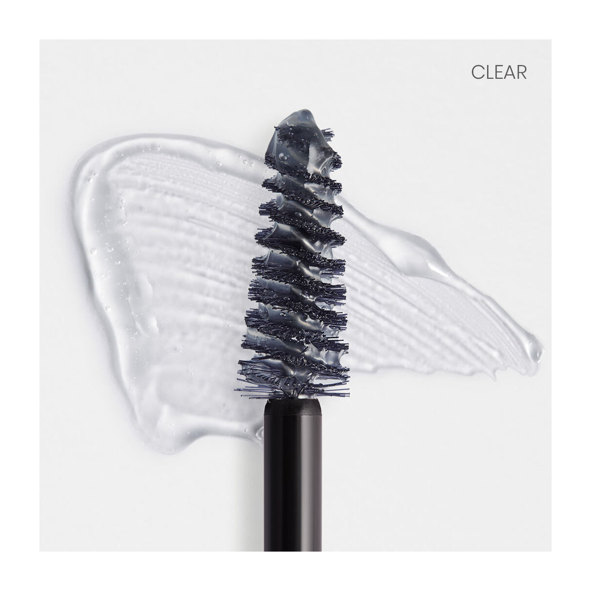 Close-up of a RevitaLash Hi-Def Brow Gel wand with clear conditioning gel on the bristles against a white background and smear. The precision styling brush ensures perfect application, with CLEAR in the top right corner.