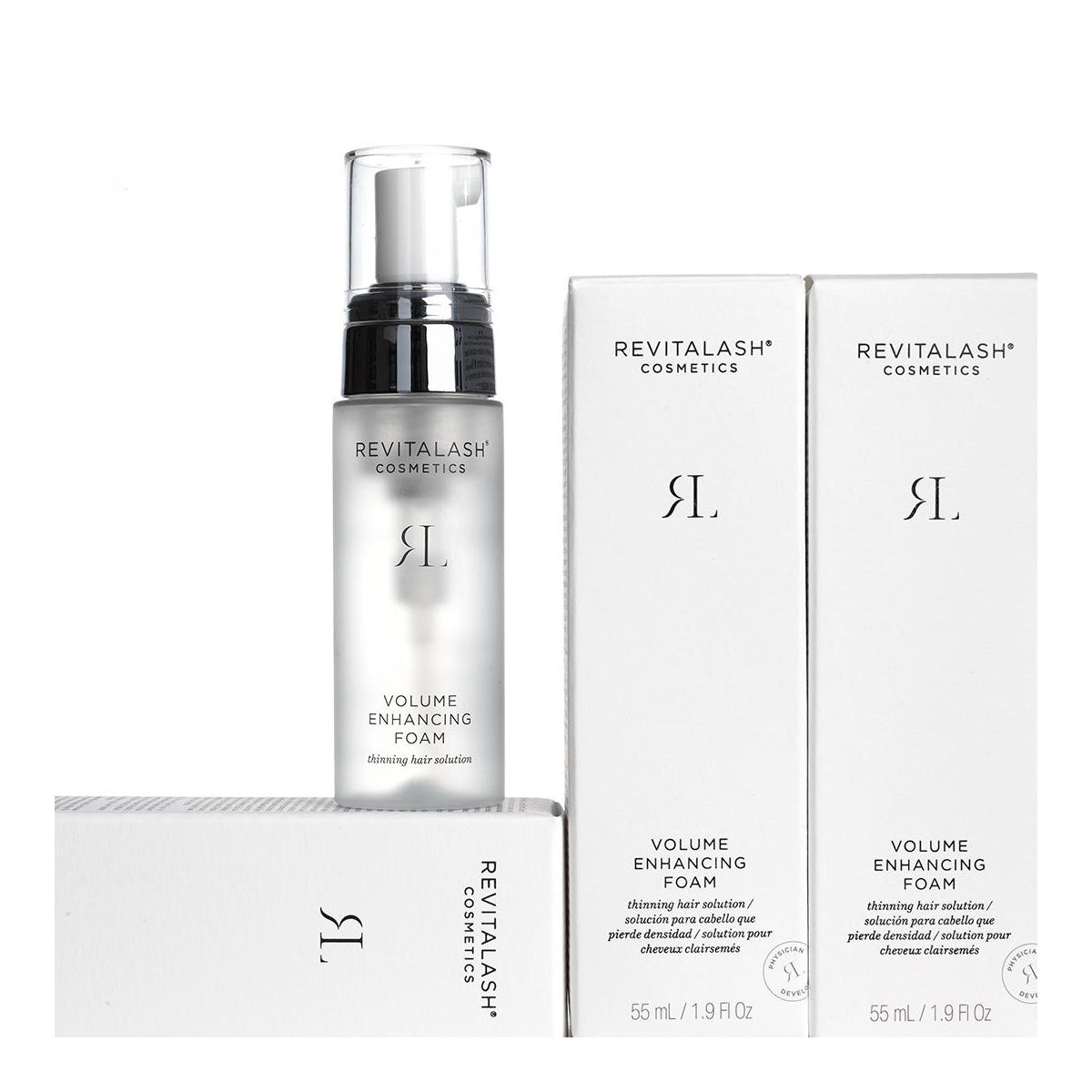 The RevitaLash Volume Enhancing Foam for Hair (55mL) bottle, with a sleek black pump top and infused with BioPeptin Complex, is displayed among three elegant boxes. This product offers an ideal solution for thinning hair, with minimalistic branding featuring black text on a crisp white background.