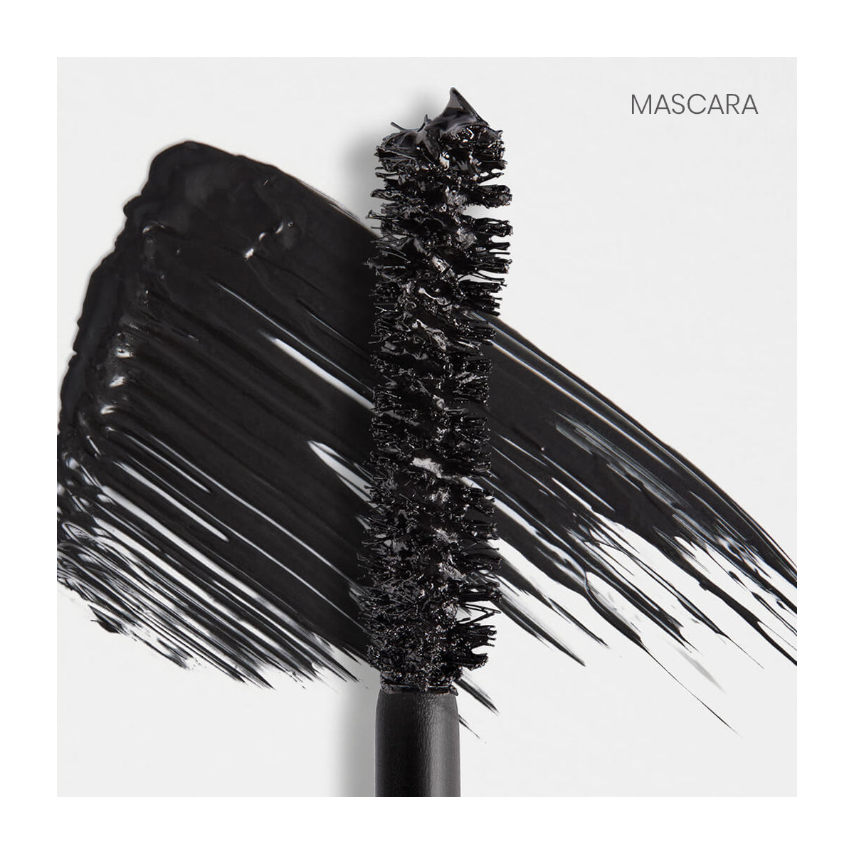 A close-up of the RevitaLash Double-Ended 2-in-1 Lash Primer & Mascara Volume Set brush shows black mascara applied thickly across a white surface in broad strokes, with MASCARA elegantly printed in the top right corner.