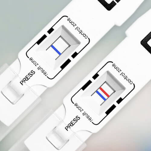 Close-up of two pregnancy tests. The test on the left shows one blue line in the result zone, indicating a negative result. The test on the right shows two blue lines in the result zone, indicating a positive result.