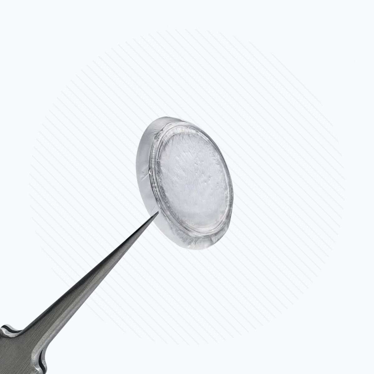 A silver needle nears a translucent circular Prokera Amniotic Membrane by BioTissue, resembling innovative corneal bandages, set against a white background with diagonal lines.