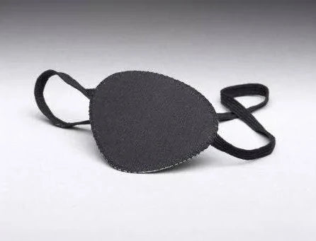 A MedPharma USA pirate eye patch, black and large with an elastic strap, rests on a smooth gray surface. Oval-shaped and made from soft fabric, it offers comfort and an adventurous spirit.