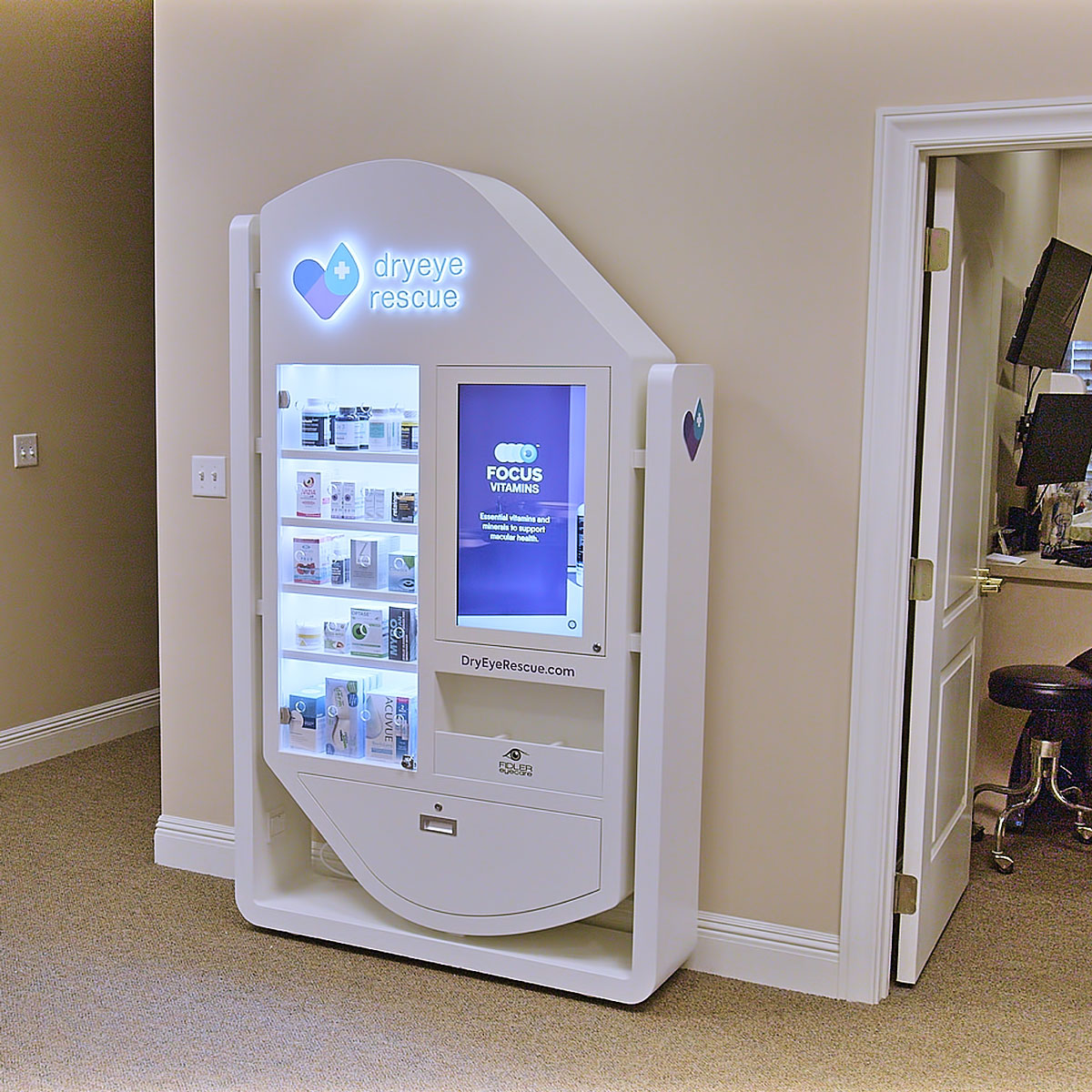 A PKG: Hybrid Standing Floor Display from DryEye Rescue, white with a digital TV screen and glass display showcasing eye care products and vitamins, stands against a beige wall. An office door is open on the right, adding depth to the scene.