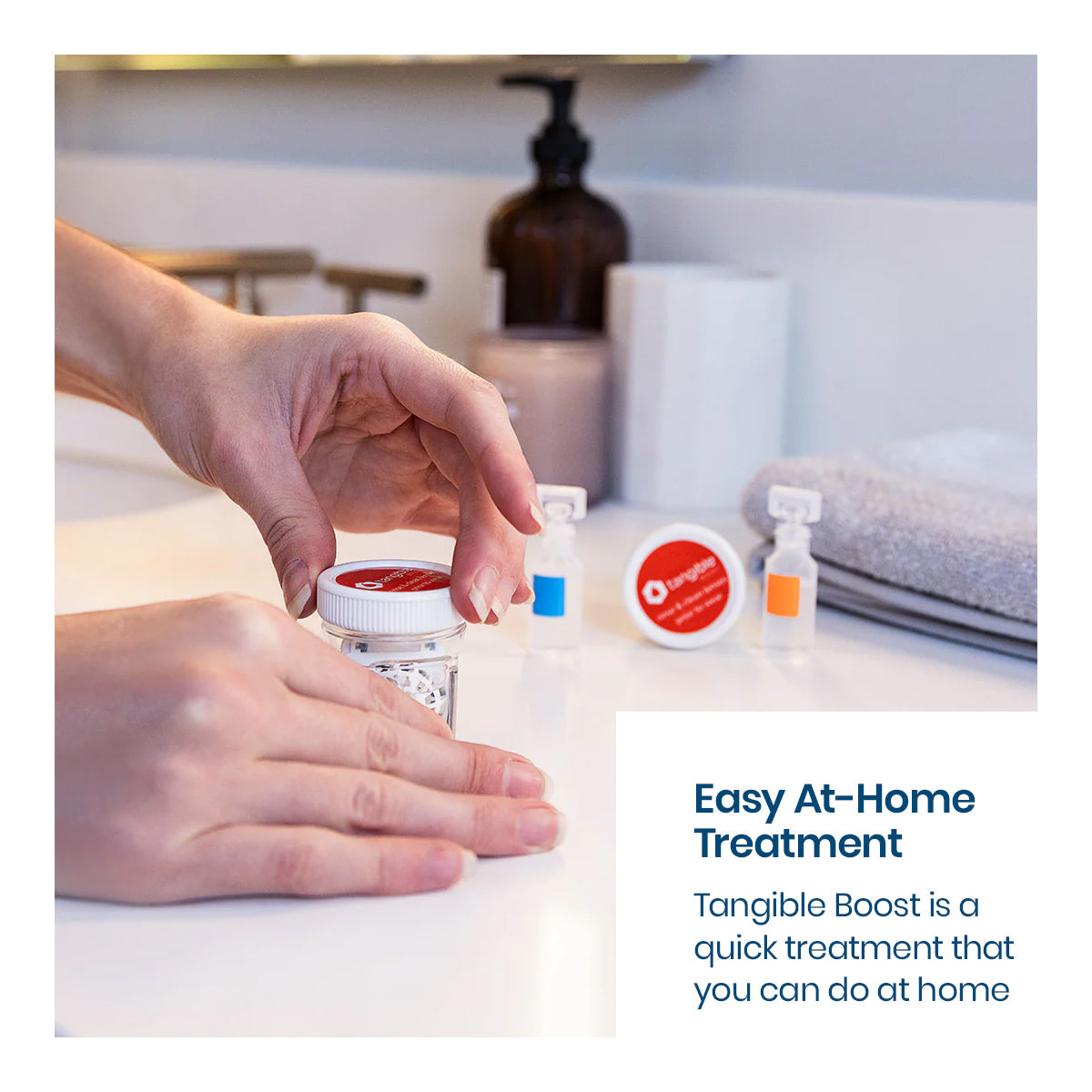 Close-up of hands opening a small bottle on a bathroom counter with other bottles and a folded towel. Text reads, Convenient At-Home Care: Tangible Boost 2-Pack restores and maintains Holy Hydra-PEG coated lenses, ideal for contact lenses to resist deposits.