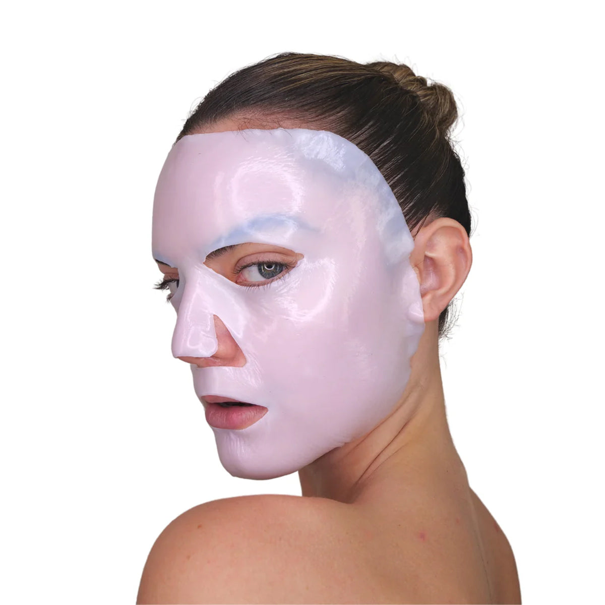 A person with a Velez Intense Hydration Cellulose Face Mask turns to the side, showcasing its skin-regeneration benefits. Their hair is in a bun, set against a plain white background.